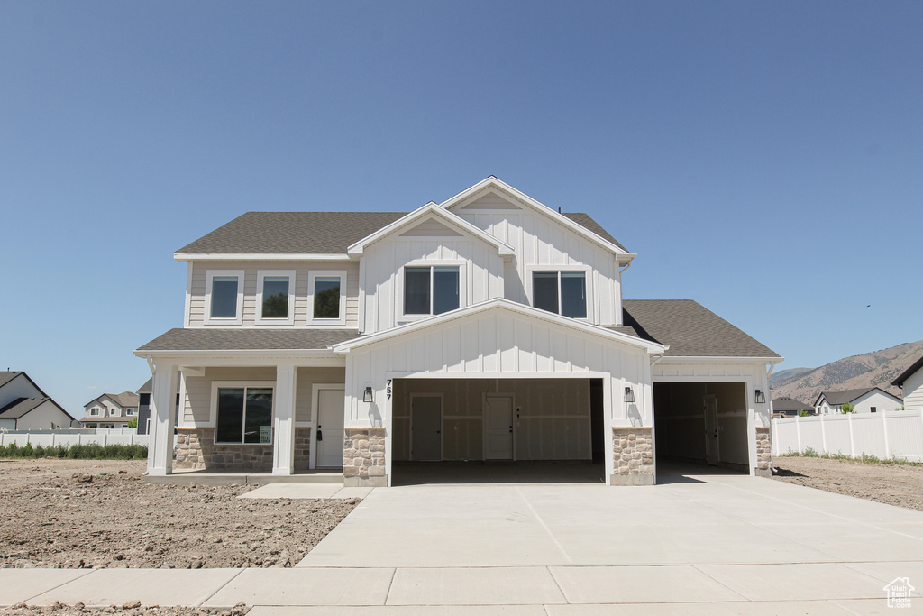 View of front of property featuring covered porch, board and batten siding, stone siding, and concrete driveway