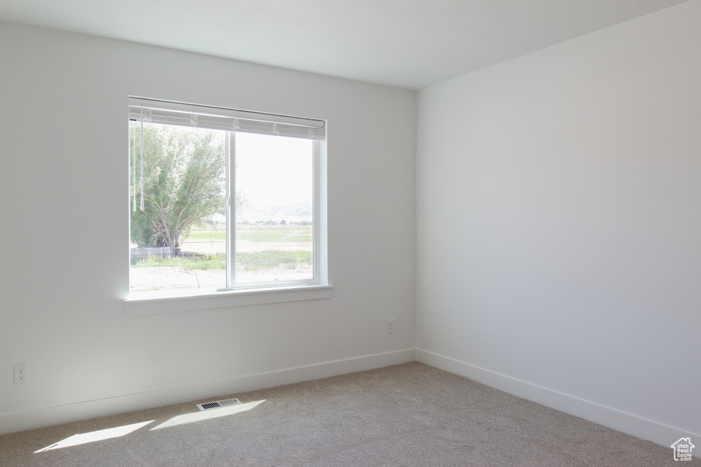 Spare room featuring carpet flooring and baseboards