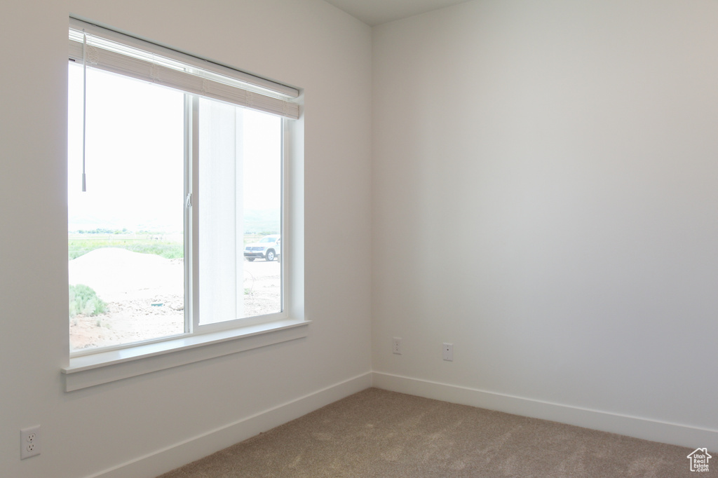 Empty room featuring light colored carpet and baseboards