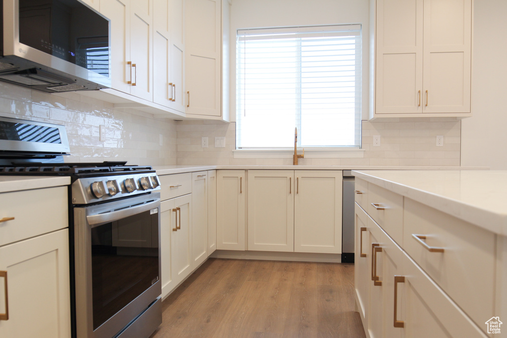 Kitchen featuring stainless steel appliances, light countertops, tasteful backsplash, and light wood finished floors
