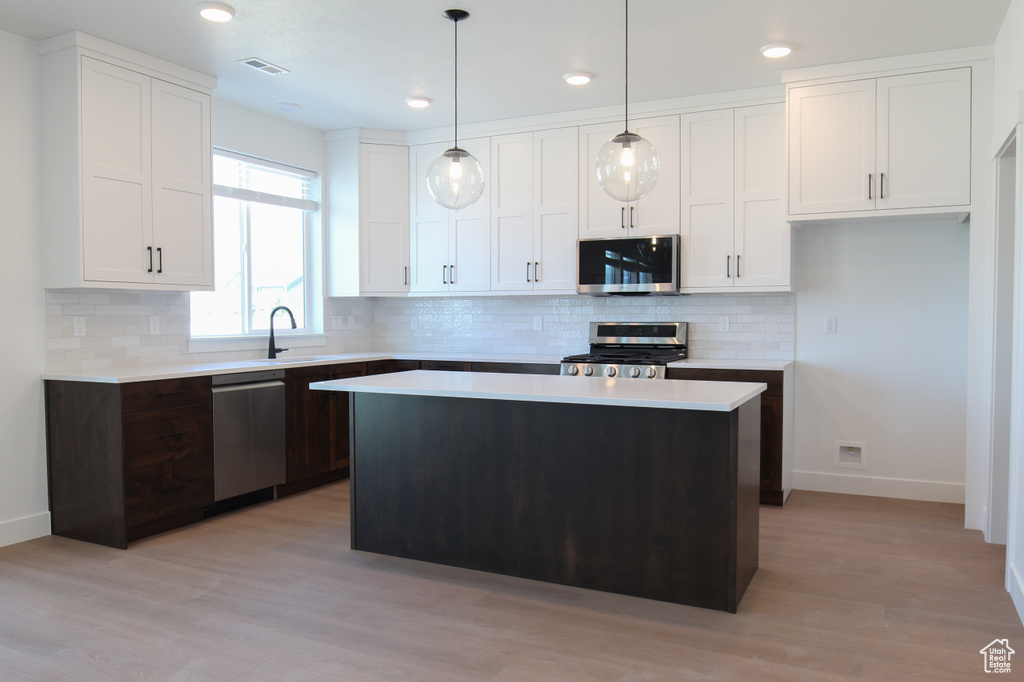 Kitchen with appliances with stainless steel finishes, light countertops, white cabinets, and recessed lighting