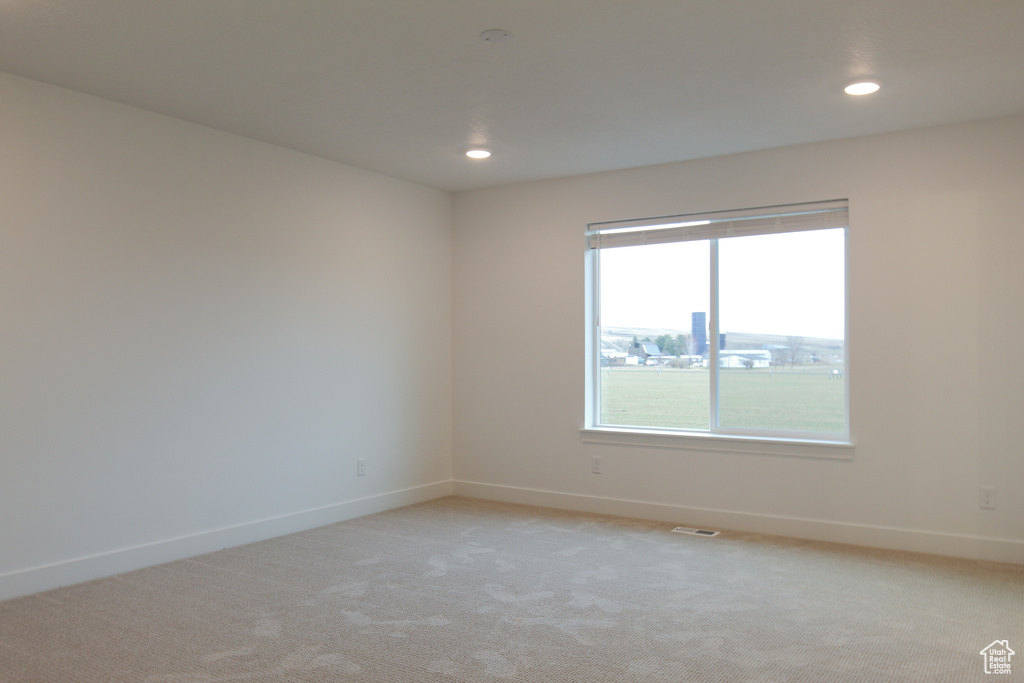 Empty room with baseboards, recessed lighting, and light colored carpet