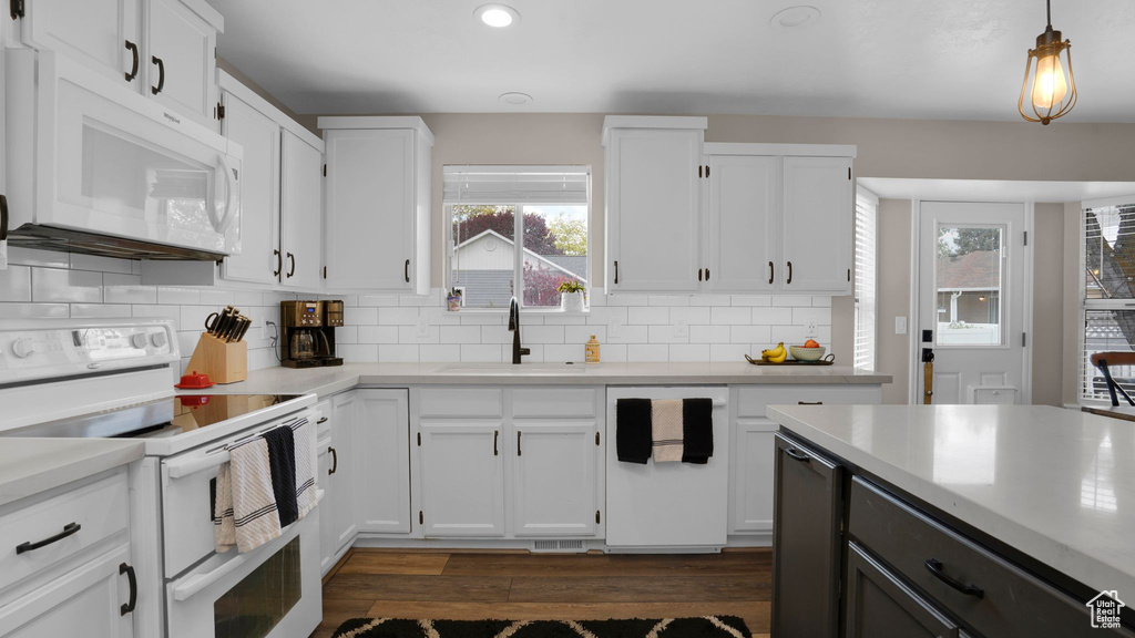 Kitchen featuring white appliances, a sink, light countertops, dark wood-style floors, and recessed lighting