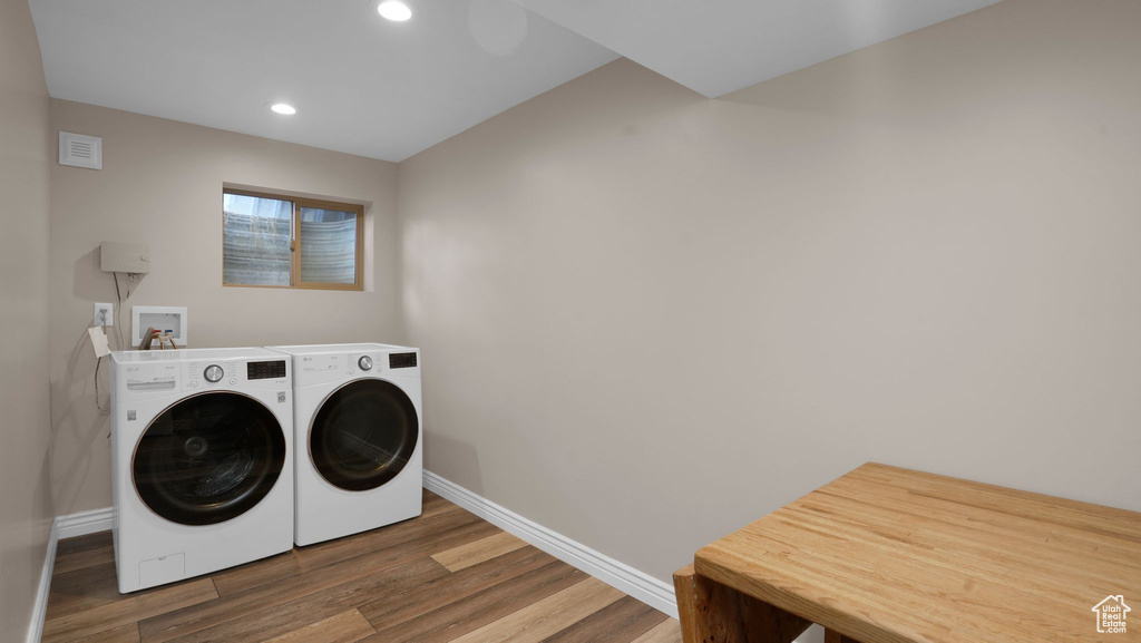Laundry area featuring baseboards, wood finished floors, washing machine and clothes dryer, and recessed lighting