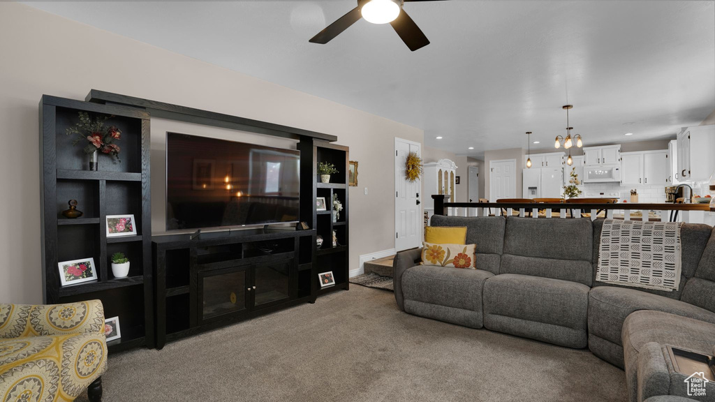 Living area featuring a ceiling fan, light colored carpet, a chandelier, and recessed lighting
