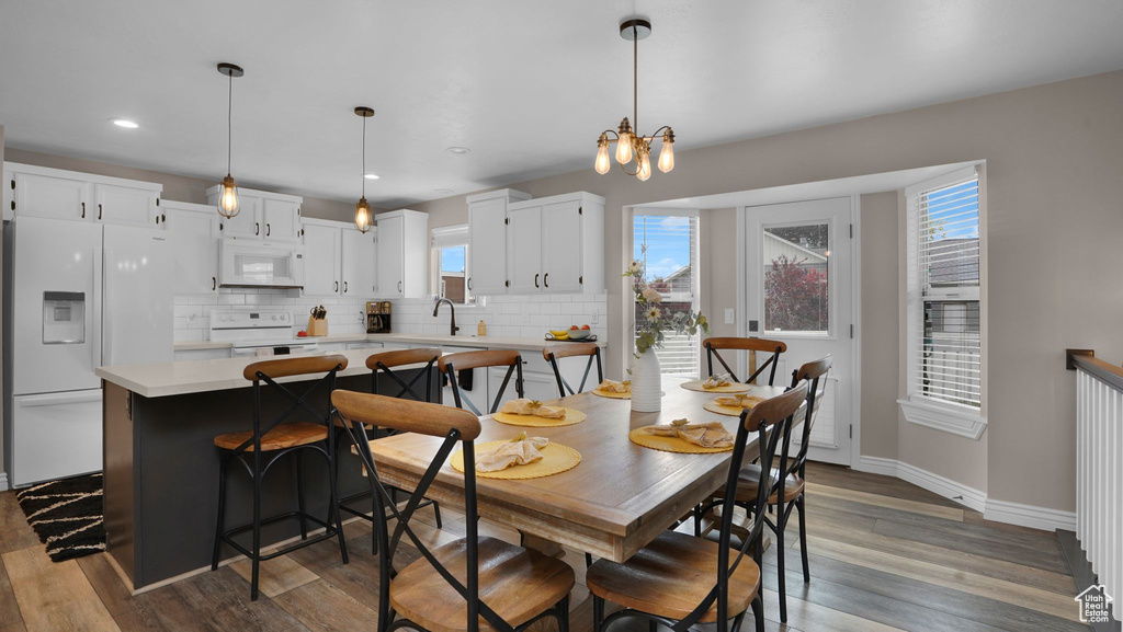 Dining room with wood finished floors, baseboards, a chandelier, and recessed lighting