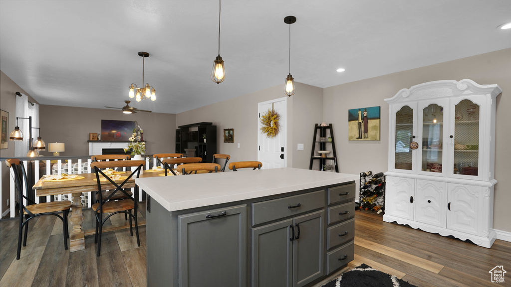 Kitchen with gray cabinets, dark wood-type flooring, hanging light fixtures, and recessed lighting