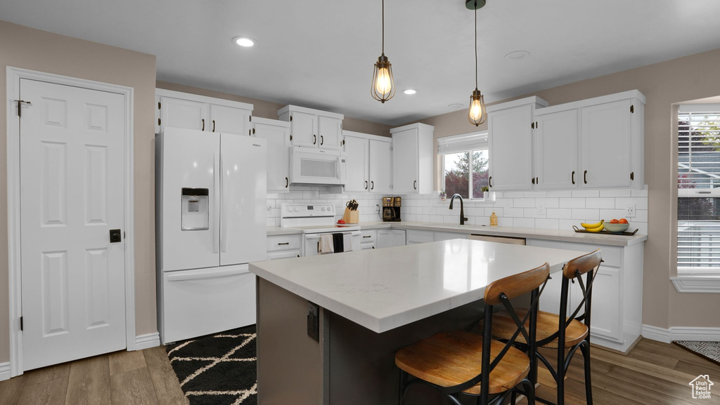 Kitchen featuring white appliances, baseboards, backsplash, wood finished floors, and recessed lighting
