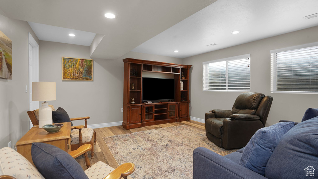 Living room with light wood finished floors, baseboards, and recessed lighting