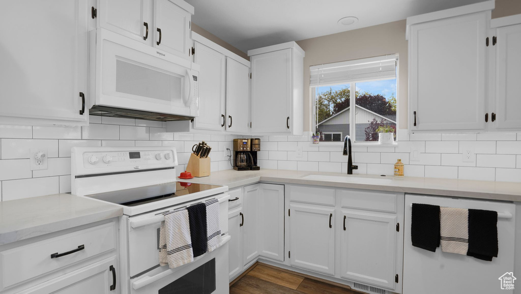 Kitchen featuring white appliances, a sink, backsplash, and white cabinetry
