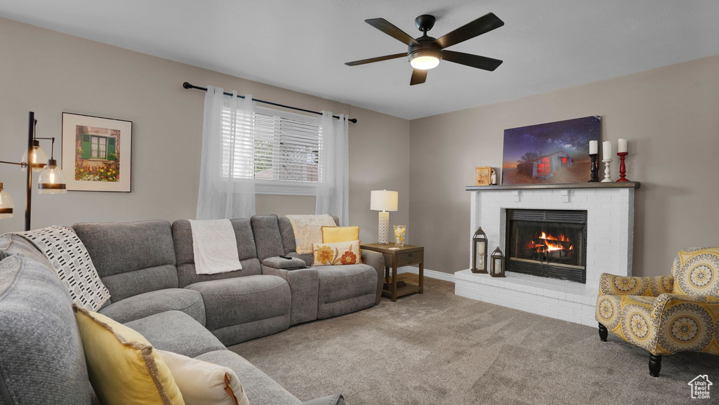 Living area featuring carpet, a brick fireplace, and a ceiling fan