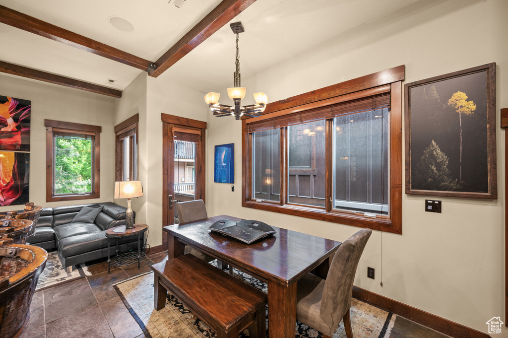Dining area with beam ceiling, a chandelier, and stone finish floors