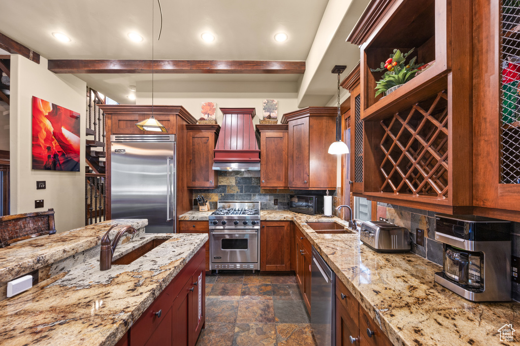 Kitchen featuring high quality appliances, custom exhaust hood, decorative backsplash, dark stone finish floors, and light stone counters