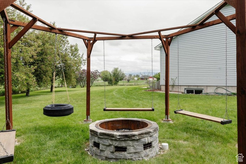 View of green lawn featuring a fire pit