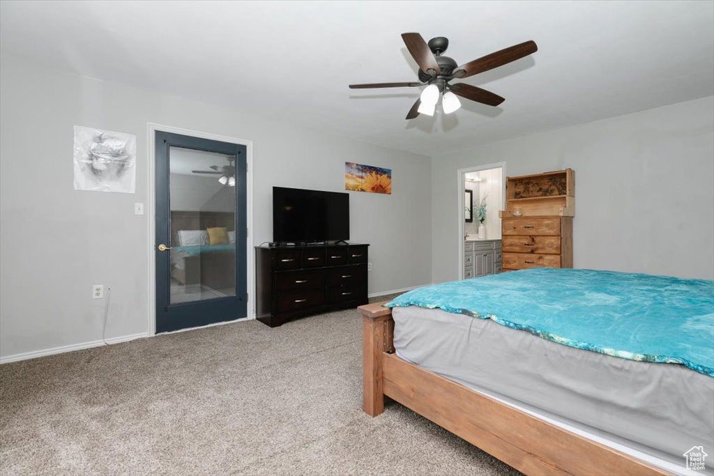 Bedroom with light colored carpet, baseboards, ceiling fan, and ensuite bathroom