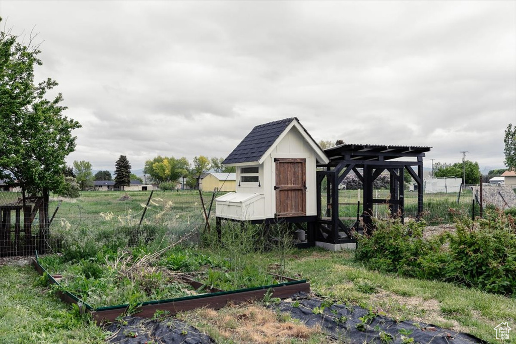 View of poultry coop featuring a vegetable garden