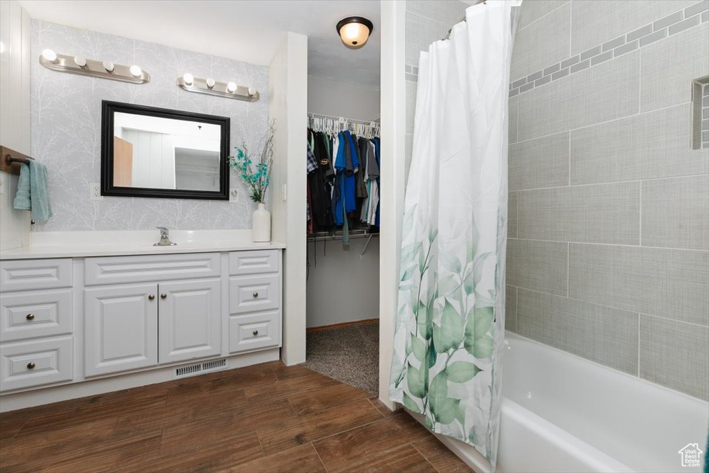 Bathroom with vanity, shower / tub combo, and wood finished floors