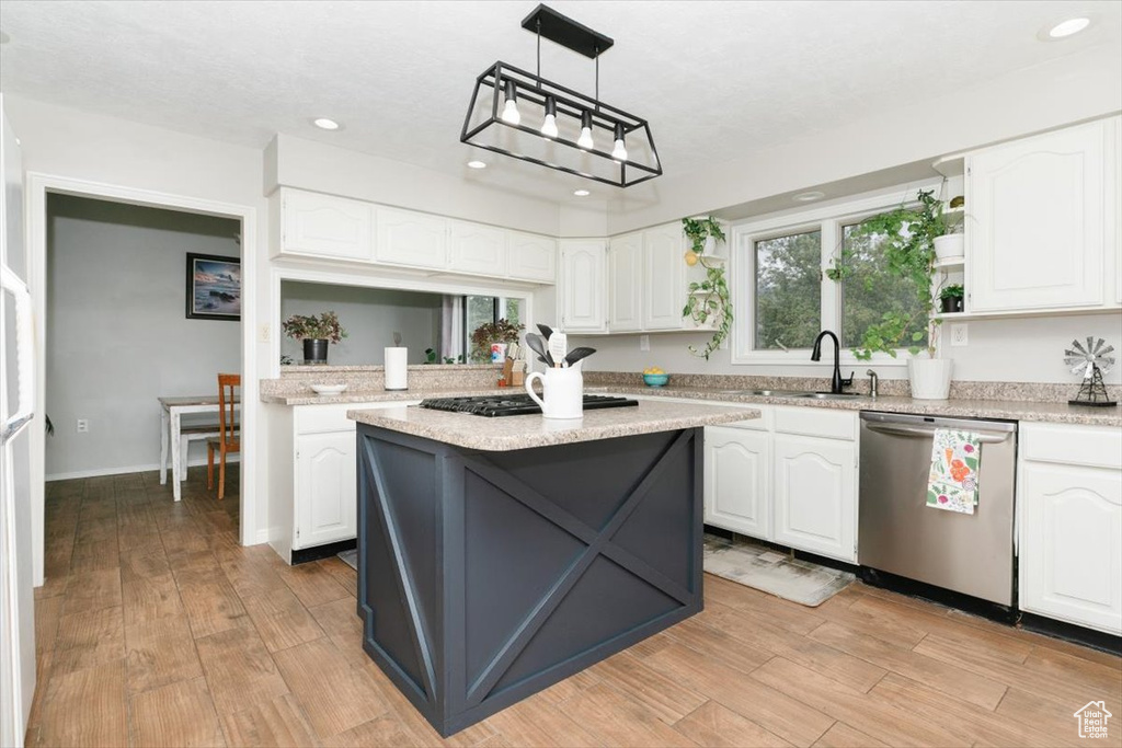 Kitchen with stainless steel appliances, a sink, white cabinets, light wood finished floors, and recessed lighting