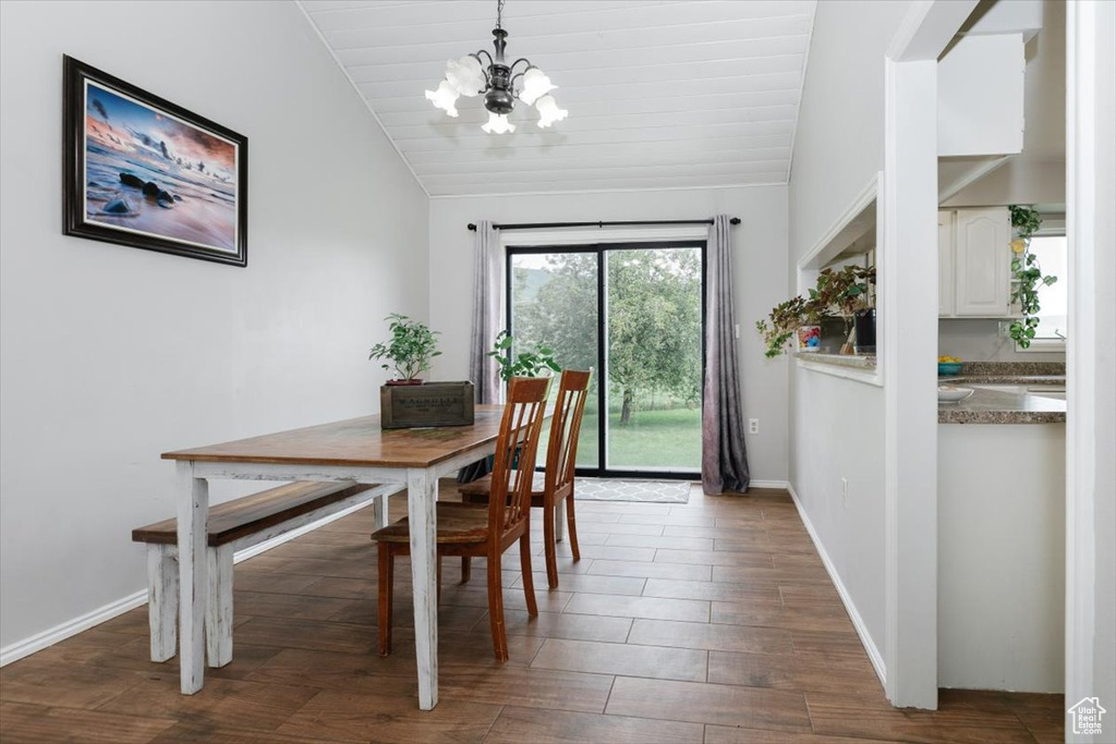 Dining area with vaulted ceiling, a chandelier, wood finished floors, baseboards, and wooden ceiling