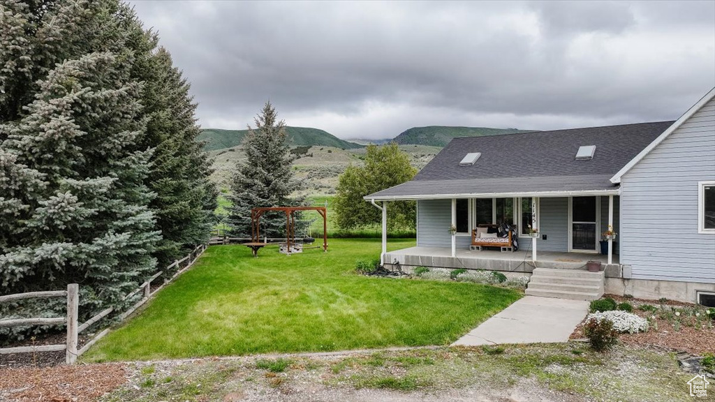 View of grassy yard with a porch and a mountain view