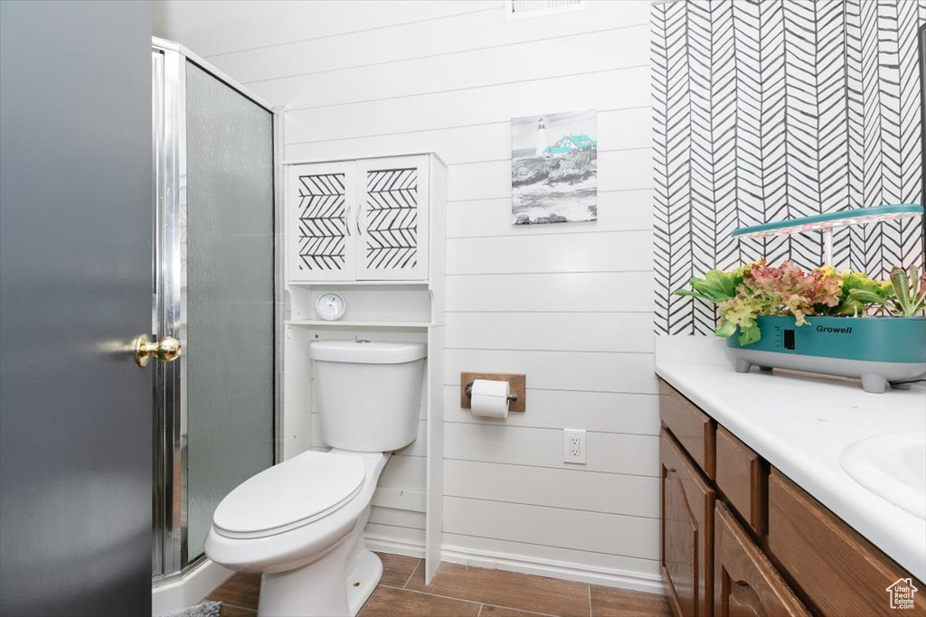 Full bath with vanity, a stall shower, wood finished floors, and toilet
