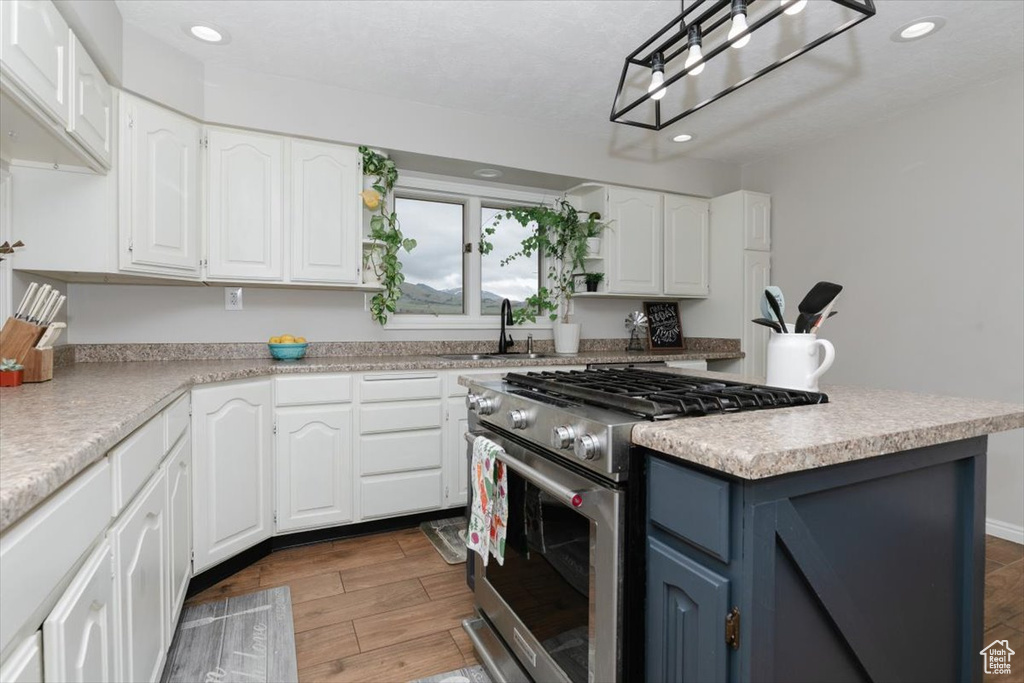 Kitchen with high end stove, a sink, white cabinets, and recessed lighting