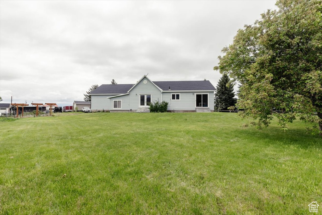 Rear view of house with entry steps and a yard