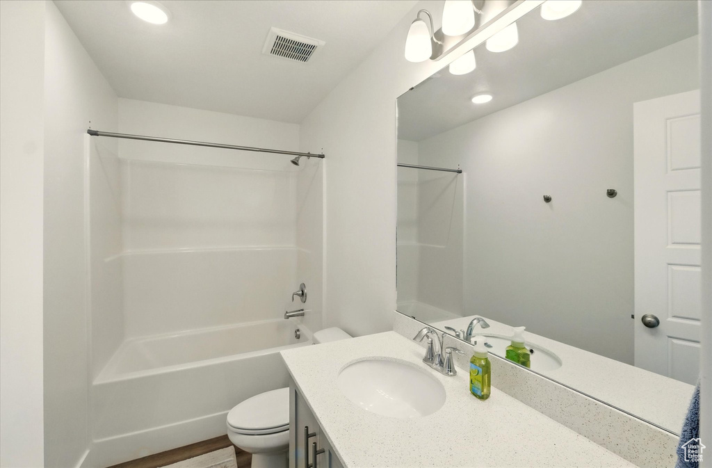 Full bathroom featuring toilet, vanity, shower / bath combination, wood finished floors, and recessed lighting