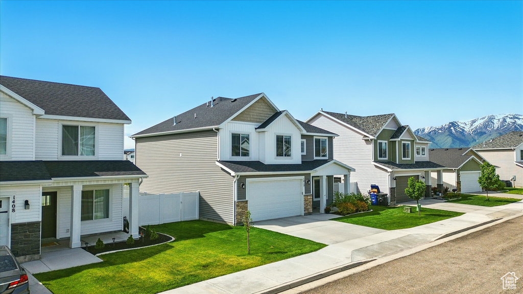 View of front facade featuring an attached garage, driveway, a mountain view, a residential view, and stone siding