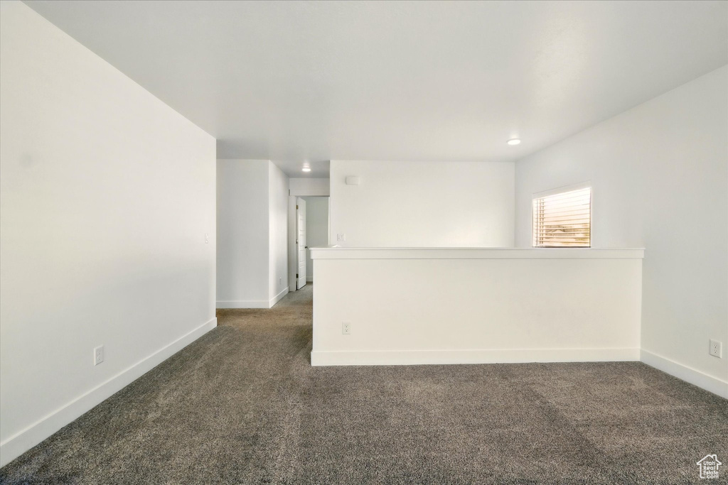 Unfurnished room featuring dark colored carpet, baseboards, and recessed lighting