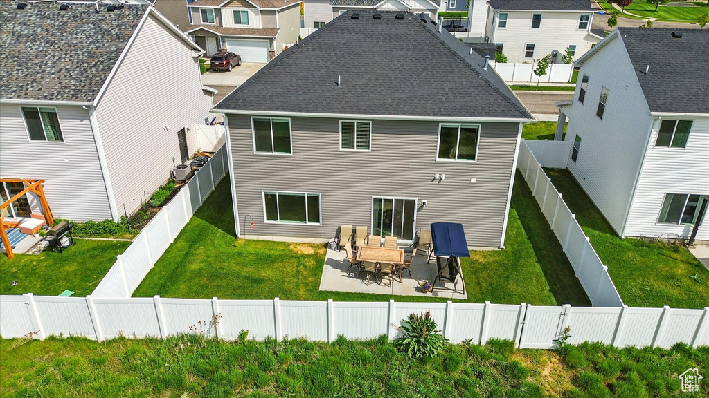 Rear view of house featuring a residential view, a patio area, a lawn, and roof with shingles