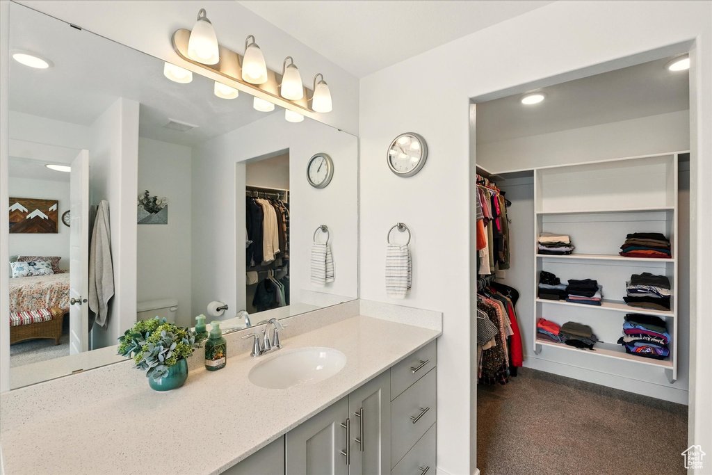 Bathroom featuring vanity, ensuite bathroom, toilet, a spacious closet, and recessed lighting