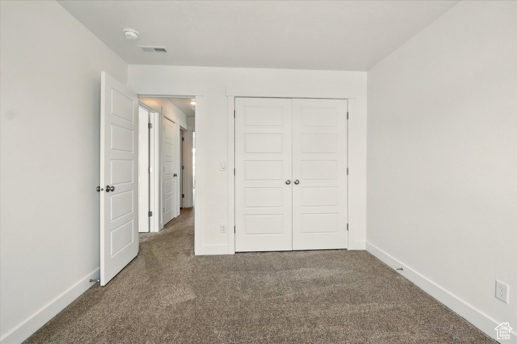 Unfurnished bedroom with carpet, baseboards, and a closet
