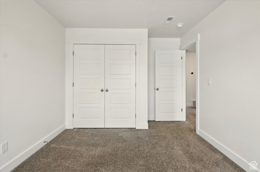 Unfurnished bedroom featuring carpet flooring, a closet, and baseboards