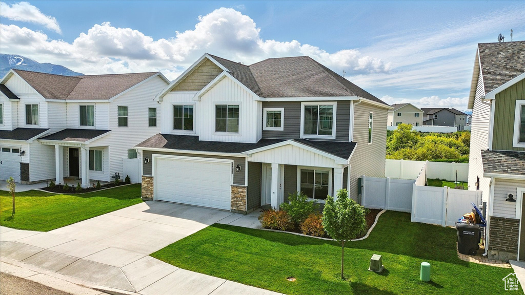 View of front of house featuring board and batten siding, concrete driveway, a garage, stone siding, and roof with shingles