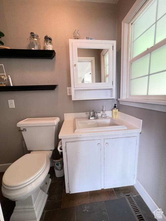 Bathroom featuring toilet, vanity, and baseboards