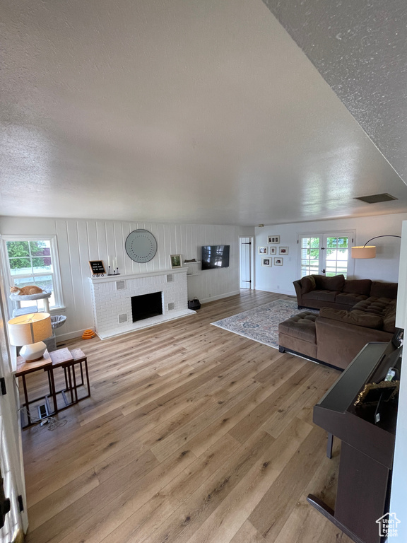 Living area with light wood-style floors, a textured ceiling, and a fireplace