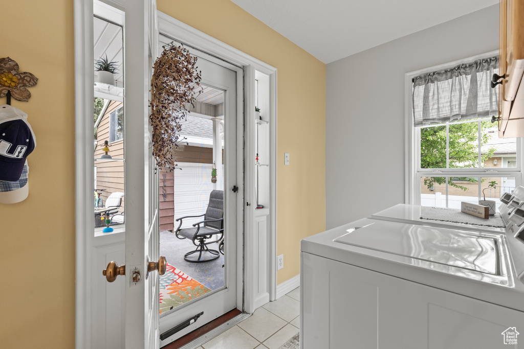 Laundry room with separate washer and dryer, light tile patterned flooring, and baseboards