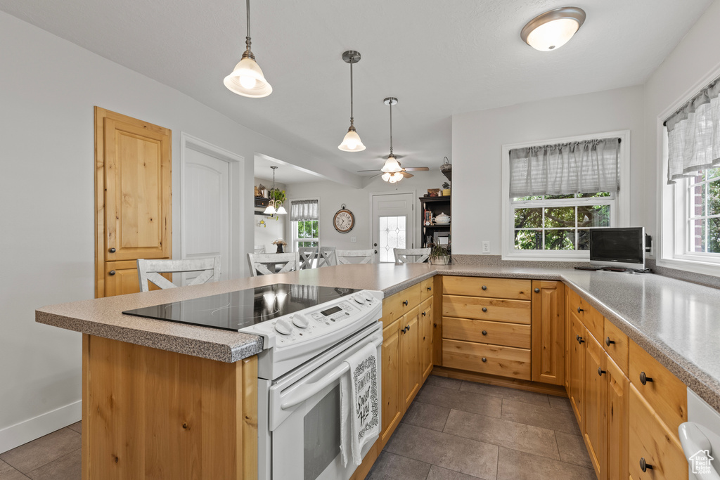 Kitchen with white range with electric cooktop, a ceiling fan, pendant lighting, a peninsula, and light brown cabinetry