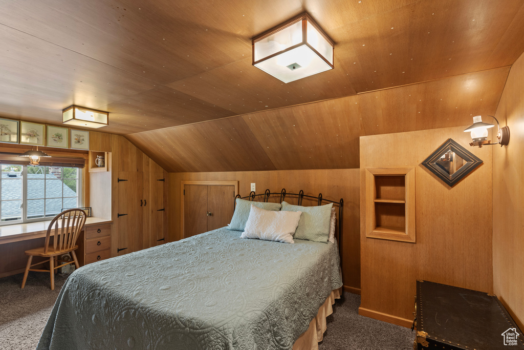 Bedroom with carpet floors, lofted ceiling, wooden ceiling, and wooden walls