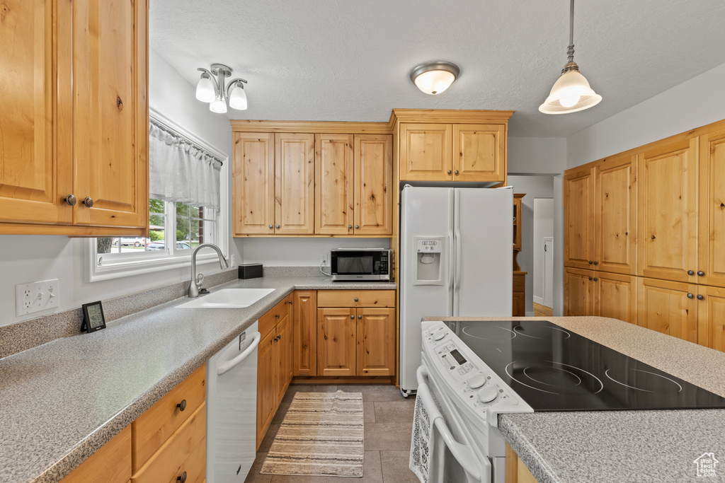 Kitchen with white appliances, a sink, pendant lighting, light countertops, and light tile patterned flooring