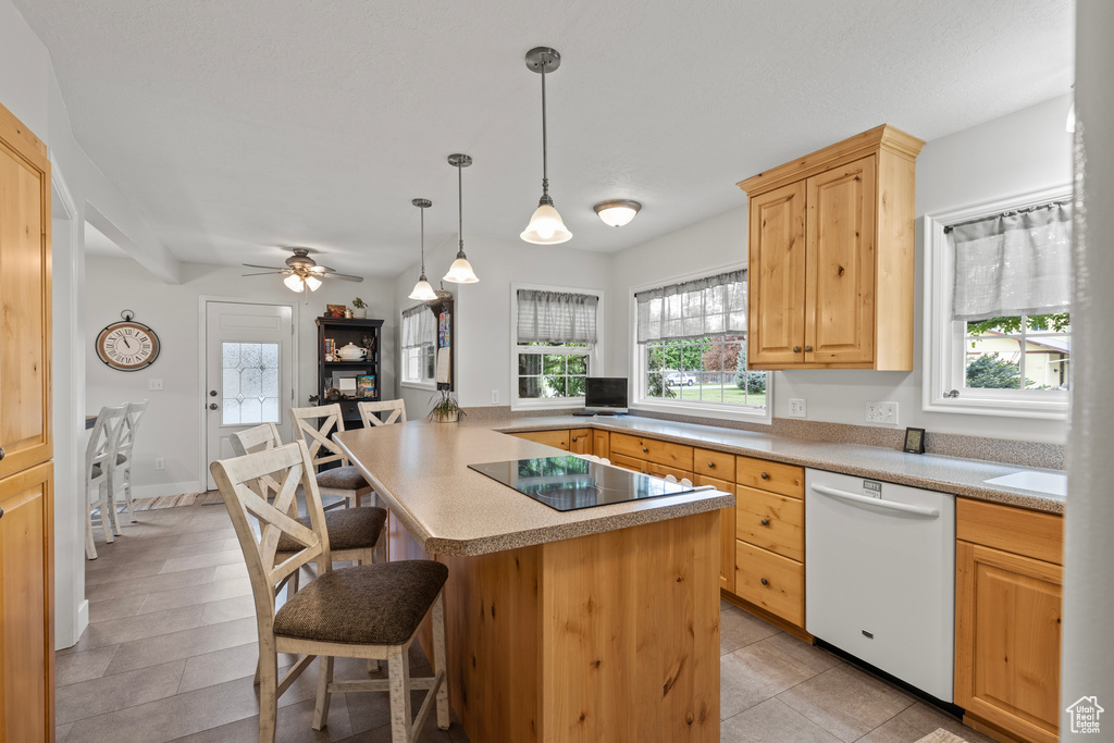 Kitchen with dishwasher, a breakfast bar area, light brown cabinets, black electric cooktop, and light countertops