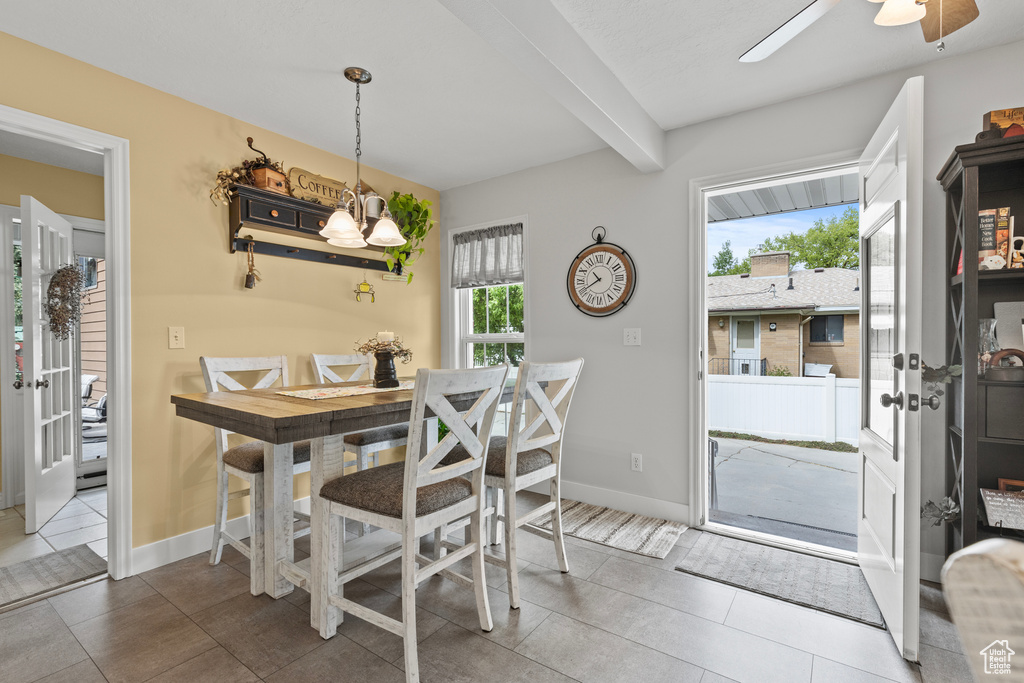 Tiled dining room with beam ceiling, baseboards, and ceiling fan