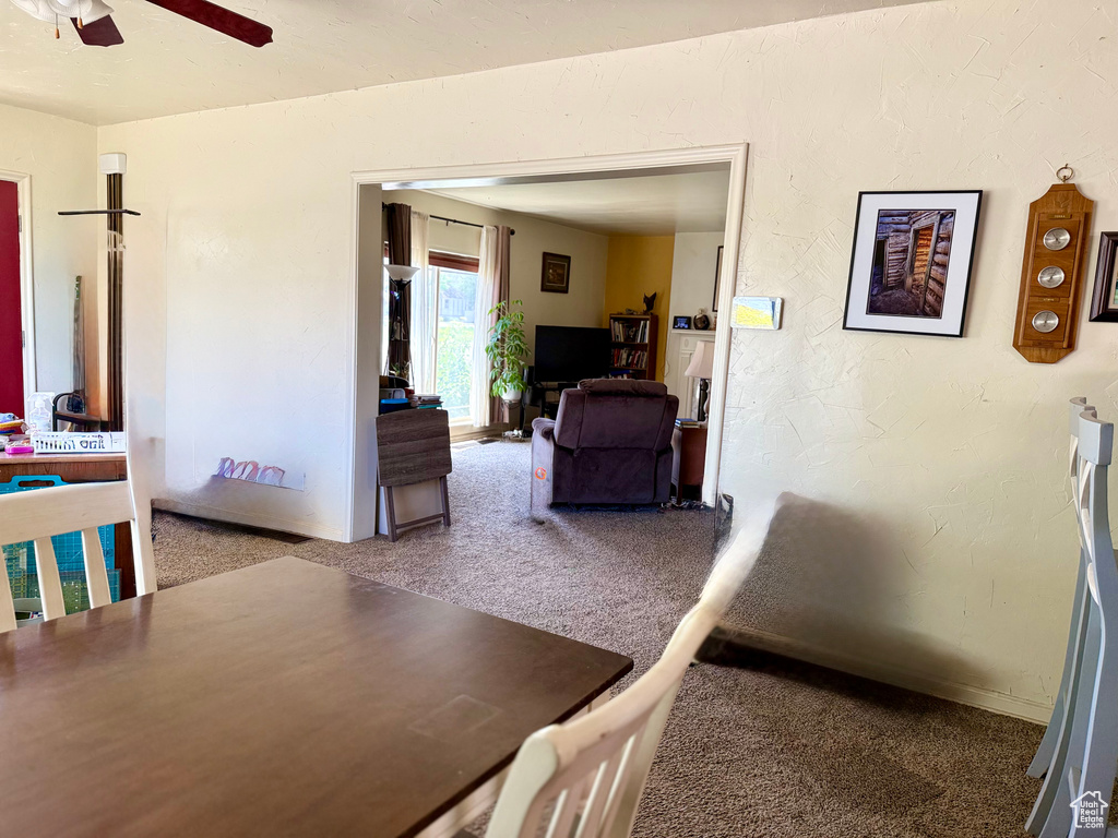 Carpeted dining area with a ceiling fan and baseboards