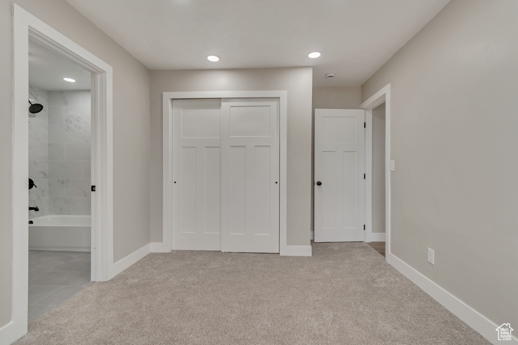 Unfurnished bedroom featuring light colored carpet, a closet, ensuite bath, recessed lighting, and baseboards