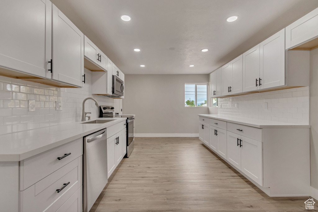 Kitchen featuring stainless steel appliances, a sink, baseboards, recessed lighting, and light countertops