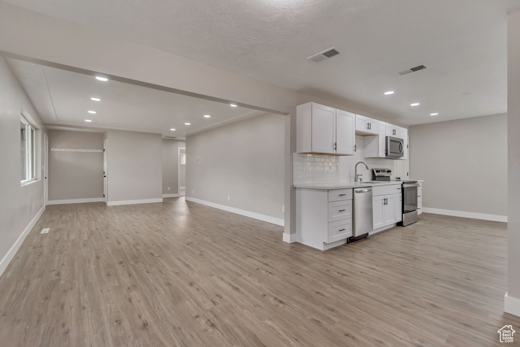 Kitchen featuring stainless steel appliances, baseboards, light countertops, light wood-style flooring, and recessed lighting