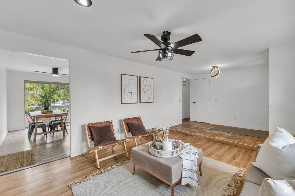 Living area with a ceiling fan, wood finished floors, and baseboards