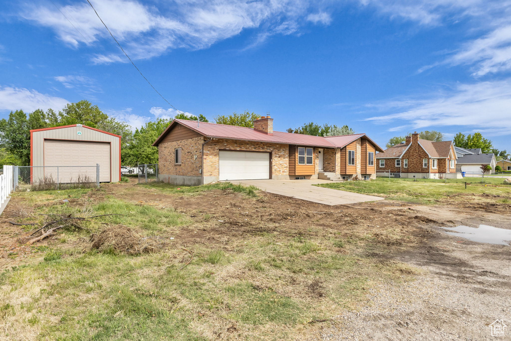 Ranch-style home with a chimney, a garage, metal roof, and brick siding