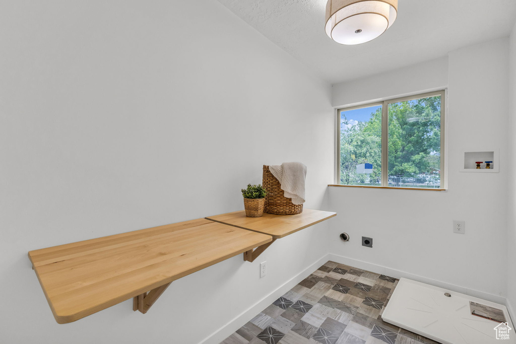 Washroom with electric dryer hookup, hookup for a washing machine, and baseboards